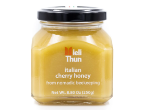 A jar of Mieli Thun Italian Cherry Honey. the jar is short and square with a black lid.