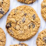 A top-down photo of a Bakehouse oatmeal raisin cookie on a marble countertop, with more cookies surrounding it.