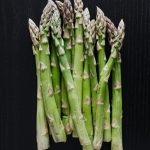 A bunch of asparagus spears on a black background.